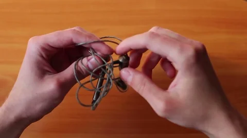 Man untangling tangled earbuds, Headphone wire tangled Stock Footage 75994786