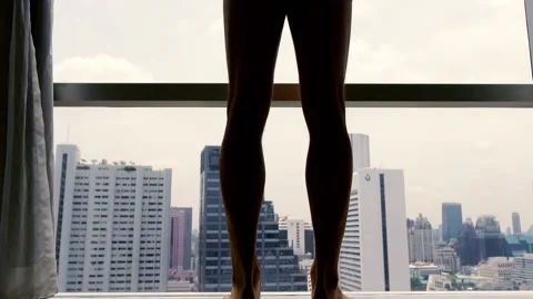 Man unveil window and looking by the window at the city, focus on legs Stock Footage 106560336
