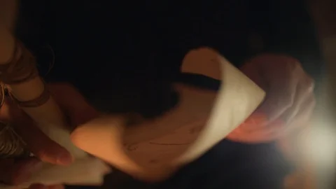 Man unwrapped one of paper scrolls, looked at the symbols, and folded it again. Stock Footage