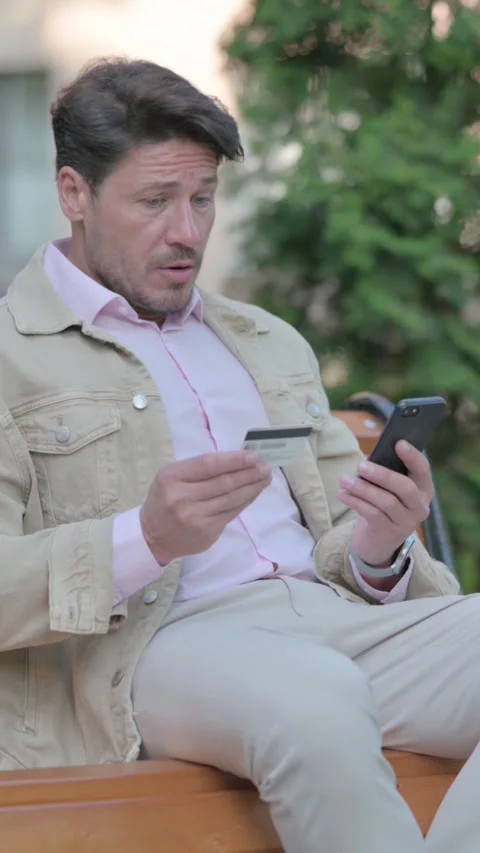 Man Upset by Online Payment Failure on Phone while Sitting Outdoor on a Bench, Video stock 326267057