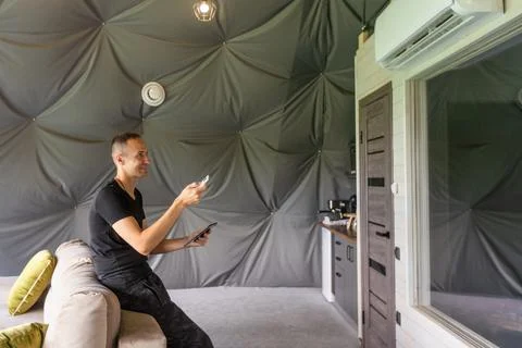 Man use application for smart home control on tablet. Interior of living room in Stock Photos