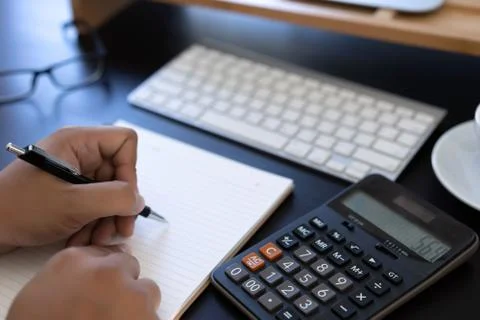 Man use calculator  make note with calculate about cost  in office Close up Stock Photos