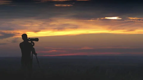 The man use the camera with tripod against the beautiful sky background Stock Footage 133721439