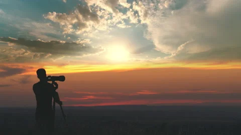 The man use the camera with tripod against the beautiful sunset background Video stock 133721618