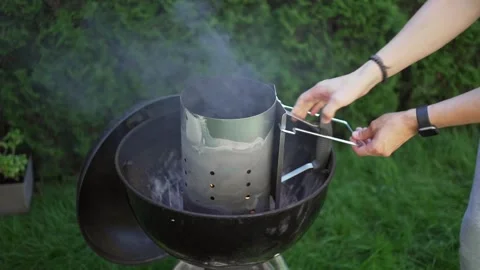 A man use a chimney starter to burn coal lumps into a garden grill. cylindrical Stock Footage 246661669