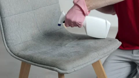 Man use detergent spray for cleaning the chair at home Stock Footage 317403089