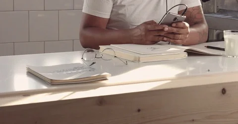Man use his smartphone then put glasses and earphones and drawing in notepad Stock Footage