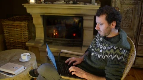 A Man use Laptop working outsource at Home near Fireplace Stock Footage 84385430