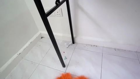 A man use left hand clean the floor beside table with broom Stock Footage 197011441