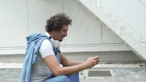 Man use mobile smart phone play video games sit outdoor Stock Footage 248305280