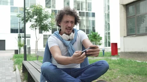 Man use mobile smart phone play video games sit outdoor Stock Footage 248305534