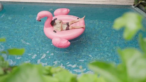 Man use phone on inflatable pink flamingo float mattress on pool party. Stock Footage 267924537