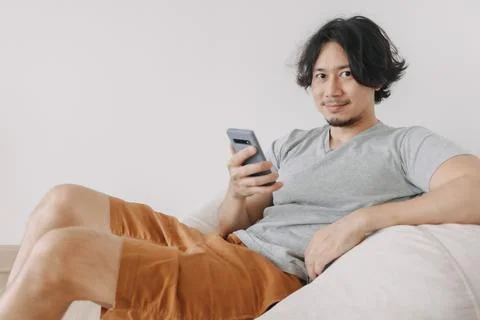 Man use smartphone while sit and relax on bean bag sofa. Stock-Fotos