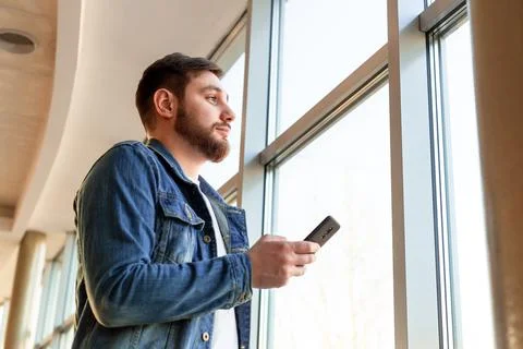Man use smartphone while standing near window in beautiful modern business ce Stock Photos