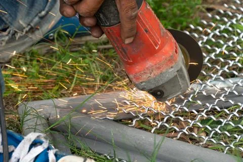 Man used angle grinder without cover guard cutting metal net to make bird cag Stock Photos