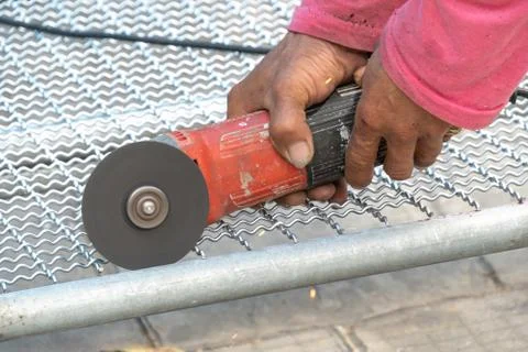 Man used angle grinder without cover guard cutting metal net to make bird cag 스톡 사진