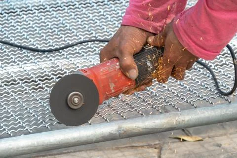 Man used angle grinder without cover guard cutting metal net to make bird cag Stock Photos