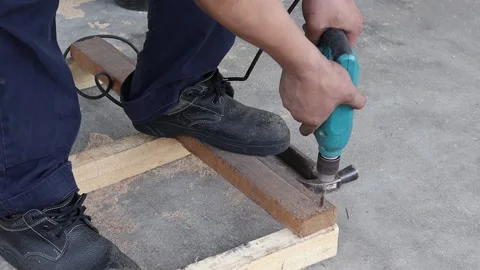 Man used electric drill is drilling wooden bar for making wooden pallet Stock Footage 151154554