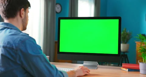 Man Uses all in one computert with Green Mock-up Screen While Sitting at the 库存影片 154849854