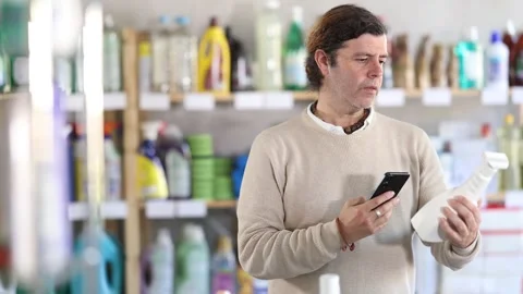 Man uses barcode to get information about glass cleaner spray in mobile Stock Footage 342128131