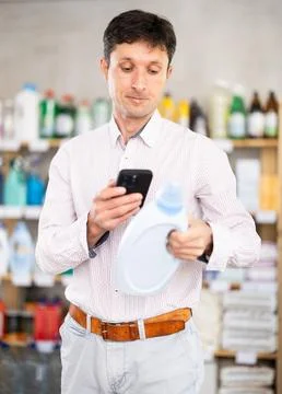 Man uses barcode to get information about liquid laundry conditioner in mobile Stock Photos