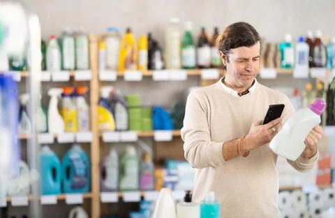 Man uses barcode to get information about liquid detergent in mobile application Stock Photos