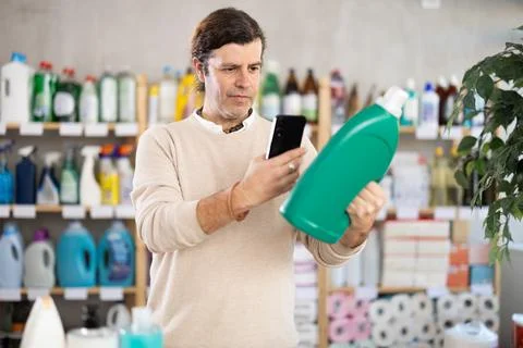 Man uses barcode to get information about liquid detergent in mobile application Stock Photos