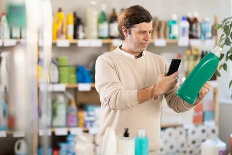 Man uses barcode to get information about liquid detergent in mobile application Stock Photos