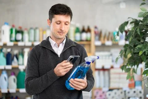 Man uses barcode to get information about glass cleaner spray in mobile Stock Photos