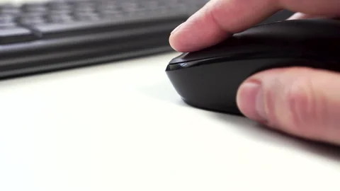 Man uses a black computer mouse on the background of a keyboard on a white Video stock 144512880