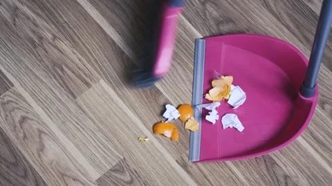 A man uses a brush and a scoop to clean up garbage at home. Stock Footage 235366654