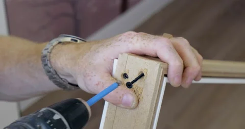 Man Uses Building Tool. Assembles Wooden Furniture. Screws Screw into Hole Stock Footage 134332649