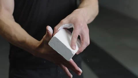 Man uses chalk while preparing for workout at gym 動画素材 323446061