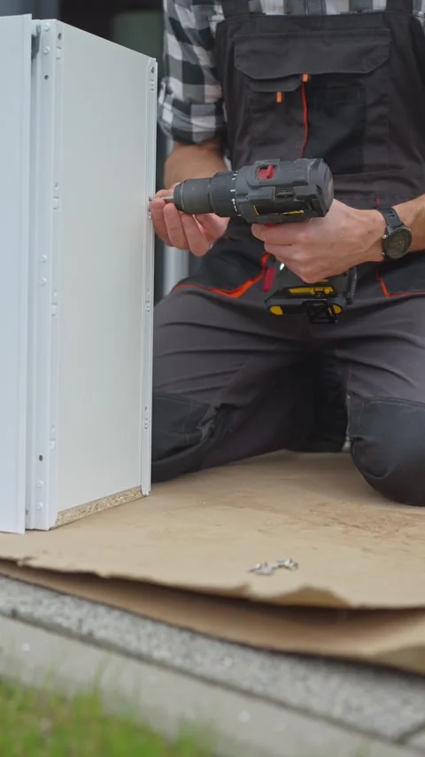 Man uses drill to drive screw into drawer side at furniture assembly workspace Stock Footage 336098969