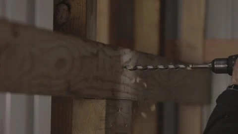 A man uses a drill to make a hole in wood in slow motion. Stock Footage 147980852