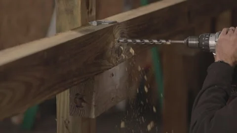 A man uses a drill to make a hole in wood in slow motion. Stock Footage 147981668