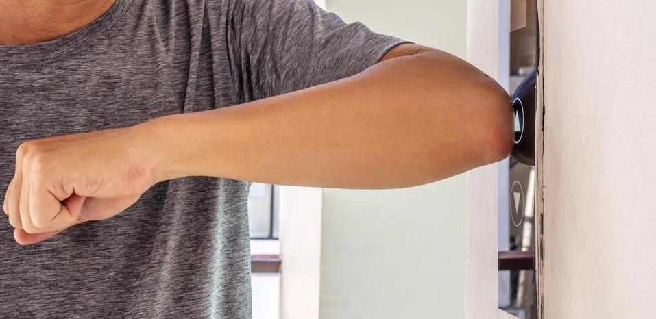 Man uses an elbow to press the elevator button to prevent the spread Stock-Fotos