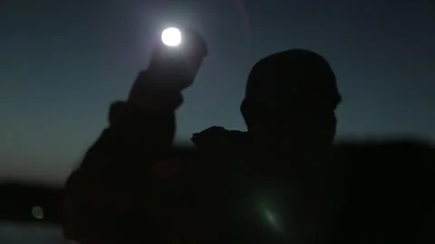 Man uses flashlight to explore at night near the lake in autumn Stock Footage 327958400