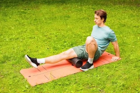 A man uses a foam roller on a mat for myofascial release and post-workout r.. Foto stock
