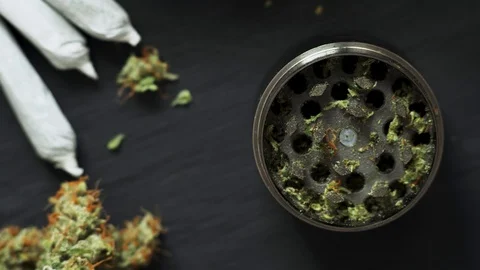 A man uses a grinder to grind marijuana weed against Video stock 85512951
