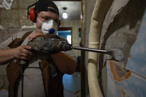 A man uses a hammer drill to remove old cement from walls A construction worker Stock Photos