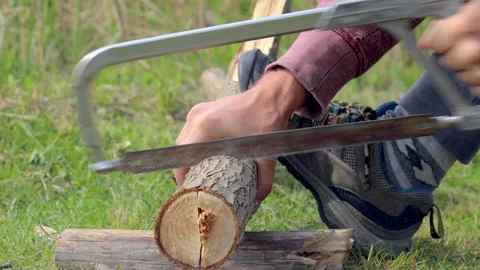 Man uses a hand saw to get some fire logs on the camping site. Stock-Footage 132382229