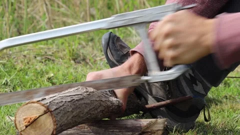 Man uses a hand saw to get some fire logs on the camping site. Stock Footage 132382397