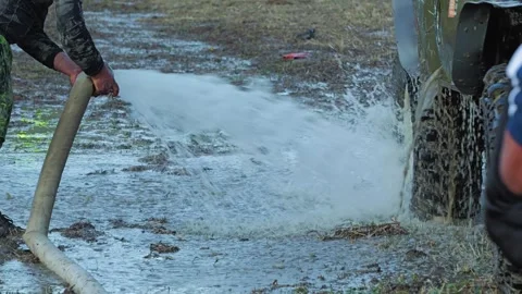 A man uses a high-pressure hose to clean a dirty SUV Stock Footage 344876669