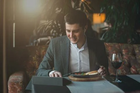 Man uses his tablet while eating healthy breakfast shakshuka - fried eggs Stock Photos