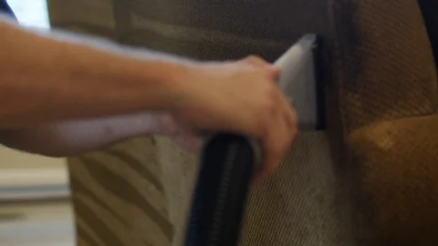 Man uses hose to clean the back of the couch Stock Footage 85865629