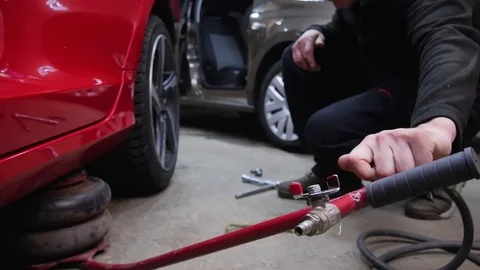A man uses a jack and removes the wheel from the car. Men's hands unscrew the Stock Footage 113109935