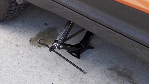 A man uses a jack to change the tire. Jacking up a vehicle. 스톡 동영상 104195459