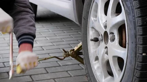A man uses a jack to raise and lower a car. Wheel replacement process. Stock Footage 166851295