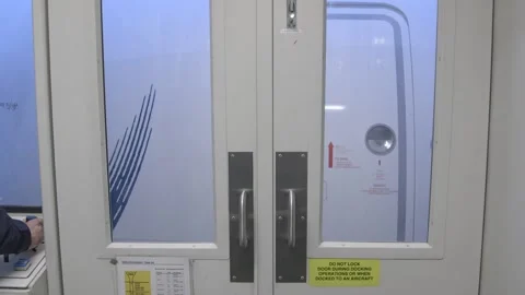 Man uses Joystick to Position Jet Bridge at Entrance to Aircraft Doors   Video stock 219707121